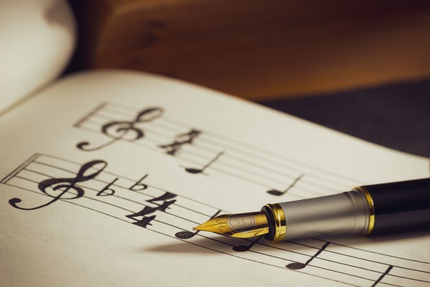 Music notes and old book on wooden table background in morning l